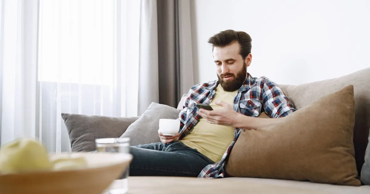 Man checking a cash advance app on his phone at home