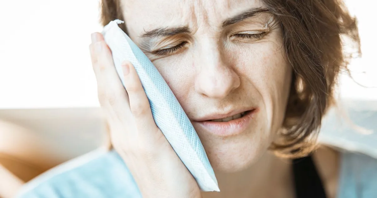 Woman holding a cold compress to her cheek - emergency dental loans for urgent toothache in Canada