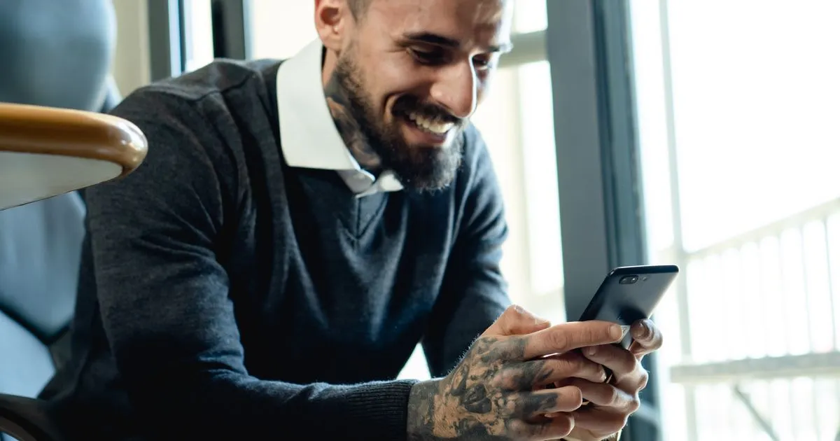 Man smiling at his phone as his loan e-transfer arrives