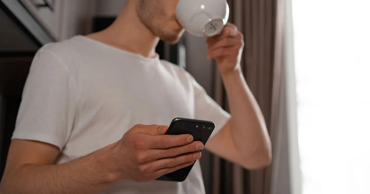 Man with a morning coffee reading a weekend loans offer on his phone before e-signing